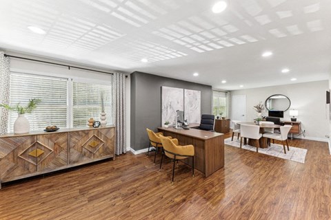 a living room with a desk and a table with chairs